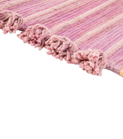 Bennd Yoga's multi-colored yoga rug features a textured, handcrafted design with prominent pink hues and tassel accents. Ideal for enhancing your yoga practice, this rug combines style and functionality. Perfect for yogis seeking a unique and vibrant addition to their routine