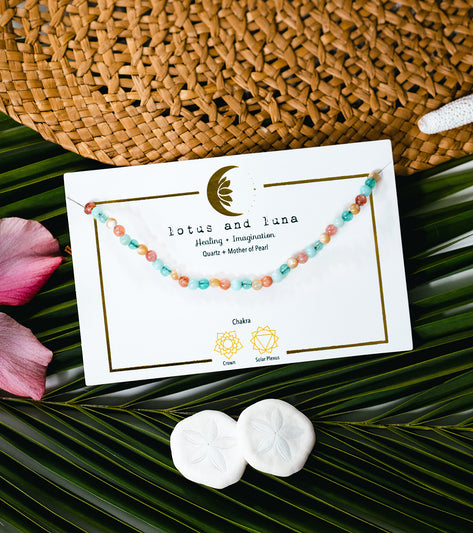 Lotus and Luna yoga necklace featuring Quartz and Mother of Pearl beads, designed for healing and imagination. The necklace is displayed on a card highlighting its connection to the Crown and Solar Plexus chakras. Perfect for enhancing your yoga practice with natural elegance.